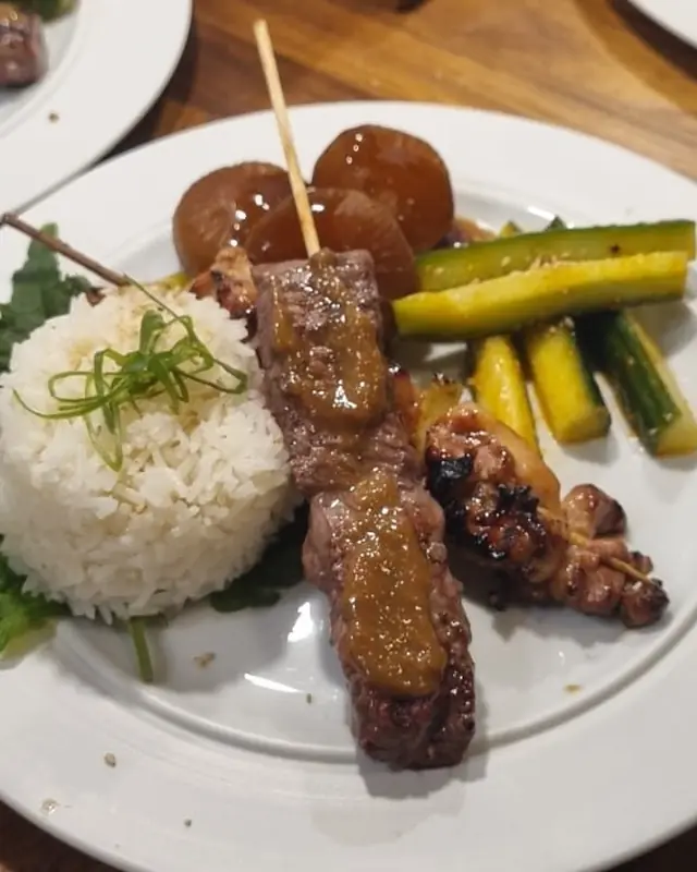 Plated skewers with rice and greens